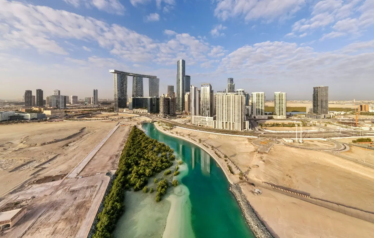 Aerial view of cleared plots and a mangrove-lined channel beside a new high-rise district