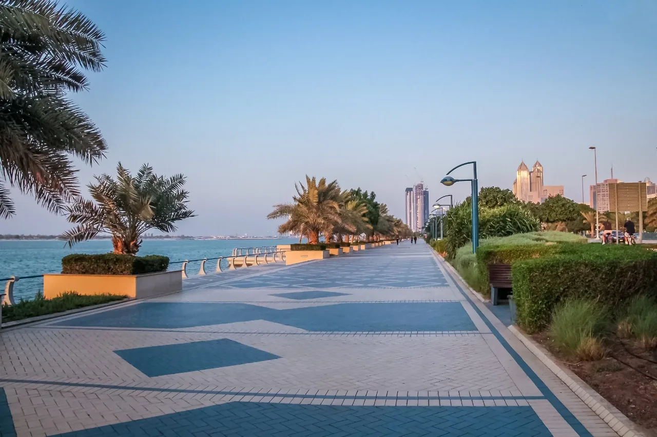 أشخاص يمشون ويركبون الدراجات على ممشى بحري في أول المساء